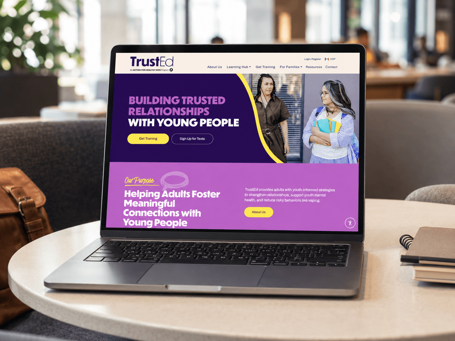 TrustEd website displayed on a laptop in a modern co-working lounge.